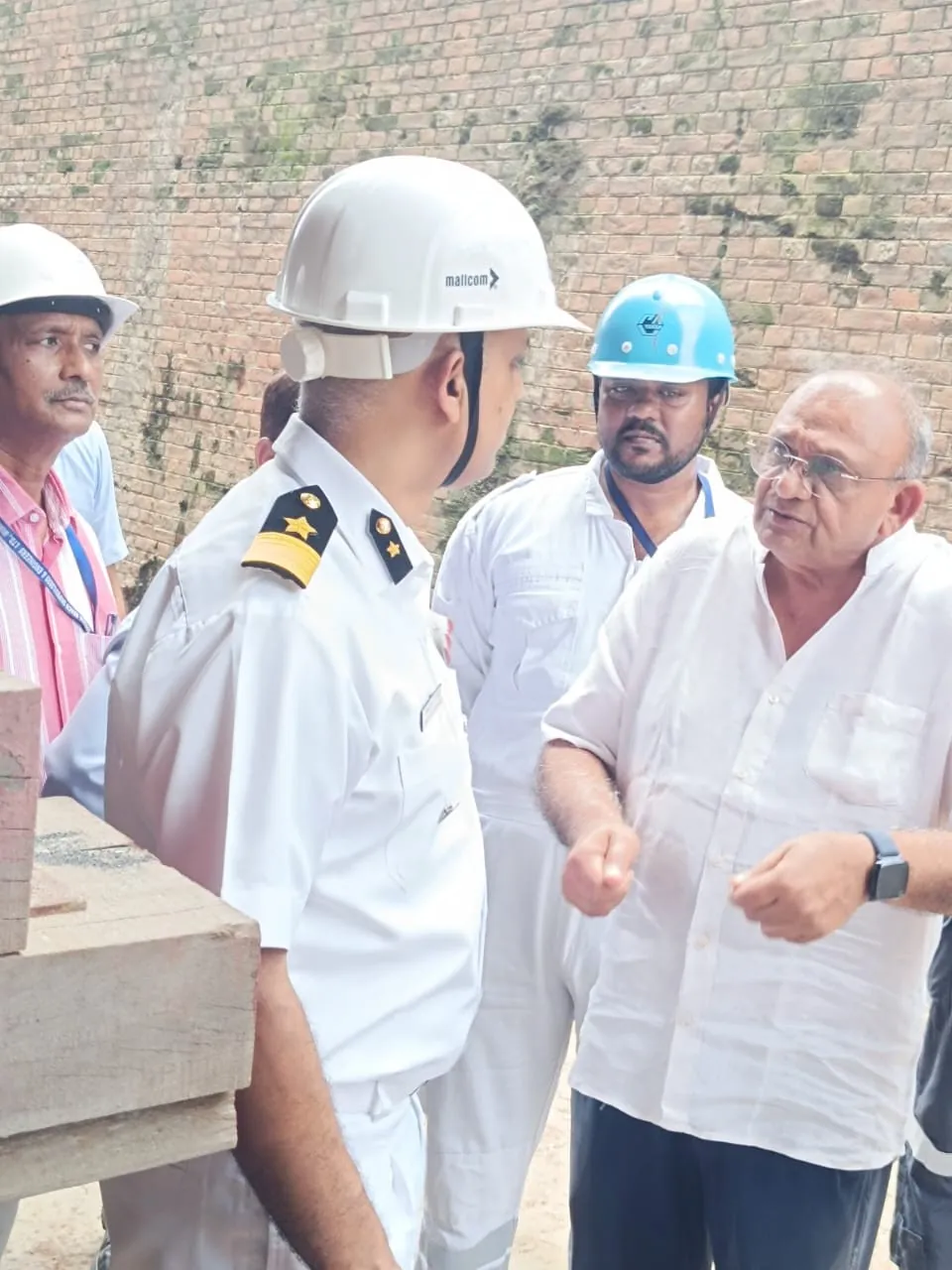 Mr Kiran Sanghvi and project representatives reviewing the INS Kalpeni refit with a naval officer.